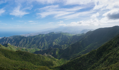 Beautiful panoramic view of the Anaga Mountains. Green hills, colorful sky and deep blue ocean. Tenerife, Canary Islands
