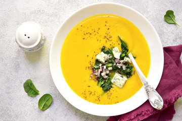 Pumpkin creamy soup with sauteed spinach and blue cheese in a white bowl .Top view.