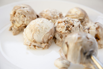 Ice cream scoops in white round plate with spoon for icecream, close-up.