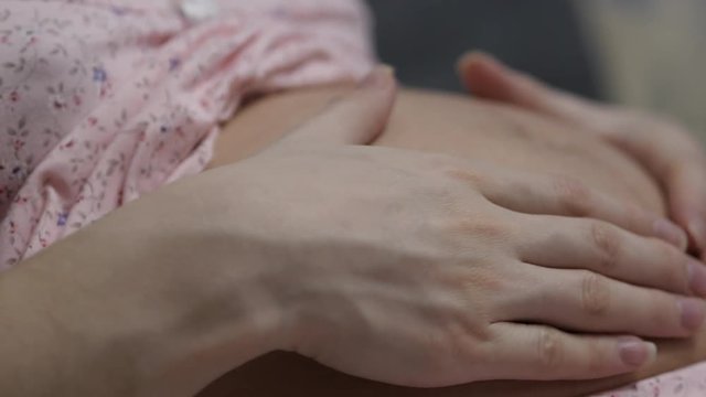 Pregnant Woman Sitting On The Couch And Touching Hand On Stomach