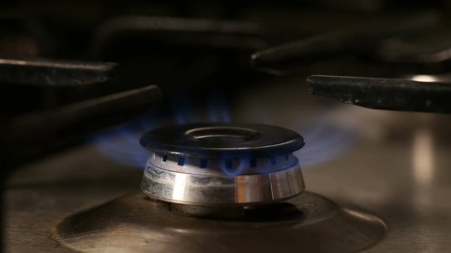 Hand lighting and turning off gas burner - close up view