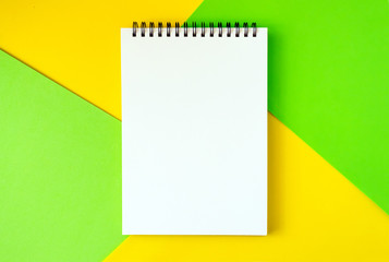 Minimal, pop art, abstract, vivid mockup with white notepad on bright green and yellow background.  Top view of open spiral blank notebook on a table. Flat lay