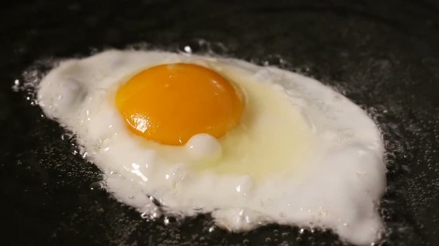 One Egg is Fried In A Frying Pan In sunflower Oil - close up view