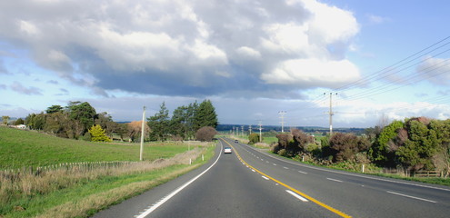 Landscape image of a cars travelling along a rural road in New Zealand.