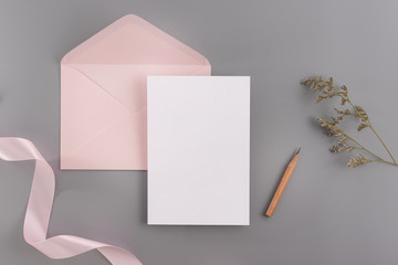 A wedding mock up concept. Wedding Invitation, envelopes, cards Papers on grey background with ribbon and decoration. Top view, flat lay, copy space