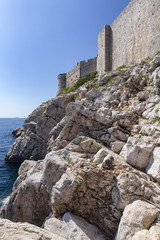 Portrait view of rocks and the exterior walls of Dubrovnik, Croatia.