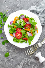 Salad. Fresh vegetable salad with tomato, onion, cucumbers, pepper, lettuce and green peas. Vegetarian salad with vegetables on plate