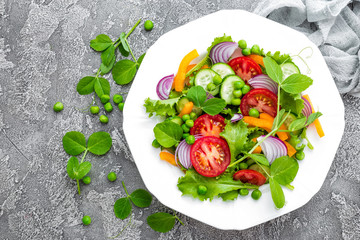 Salad. Fresh vegetable salad with tomato, onion, cucumbers, pepper, lettuce and green peas. Vegetarian salad with vegetables on plate