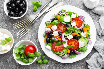 Greek salad. Fresh vegetable salad with tomato, onion, cucumbers, basil, pepper, olives, lettuce and feta cheese. Greek salad on plate