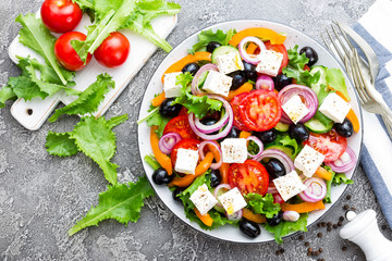 Greek salad. Fresh vegetable salad with tomato, onion, cucumbers, pepper, olives, lettuce and feta cheese. Greek salad on plate
