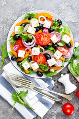 Greek salad. Fresh vegetable salad with tomato, onion, cucumbers, pepper, olives, lettuce and feta cheese. Greek salad on plate