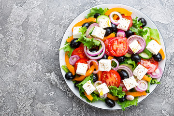 Greek salad. Fresh vegetable salad with tomato, onion, cucumbers, pepper, olives, lettuce and feta cheese. Greek salad on plate