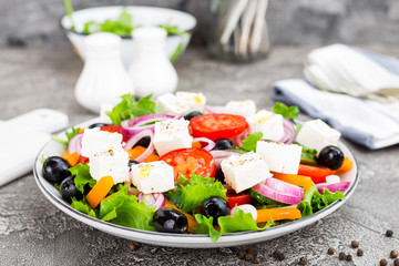 Greek salad. Fresh vegetable salad with tomato, onion, cucumbers, pepper, olives, lettuce and feta cheese. Greek salad on plate