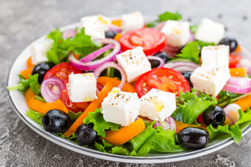 Greek salad. Fresh vegetable salad with tomato, onion, cucumbers, pepper, olives, lettuce and feta cheese. Greek salad on plate