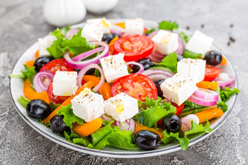 Greek salad. Fresh vegetable salad with tomato, onion, cucumbers, pepper, olives, lettuce and feta cheese. Greek salad on plate