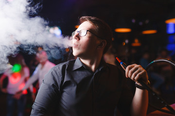 The man smokes a hookah in the club