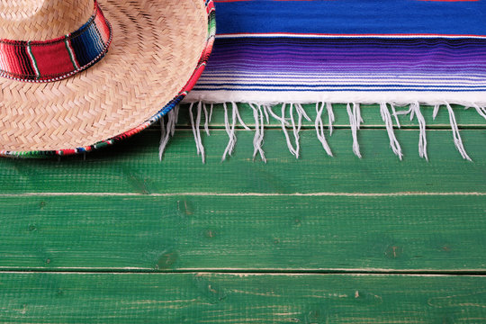 Mexico cinco de mayo fiesta carnival traditional green wood background border mexican sombrero and serape rug or blanket photo