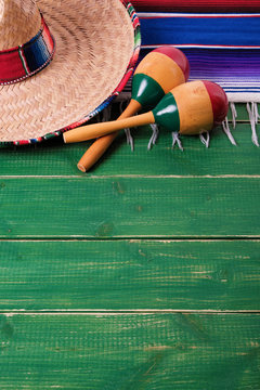 Mexico cinco de mayo fiesta carnival traditional green wood background border mexican sombrero maracas and serape rug or blanket photo vertical
