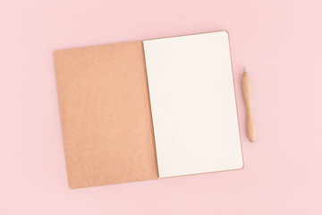 Pink desktop with notebook open page and pen.