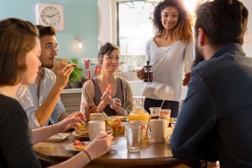 bunch of multi-ethnic friends gathered around a table for breakf