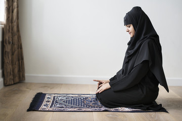 Muslim woman praying in Tashahhud posture - obrazy, fototapety, plakaty