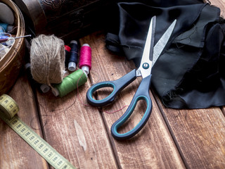 scissors centimeter roll and thread on a wooden table
