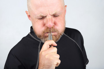 Bearded man in a black jacket blowing a whistle