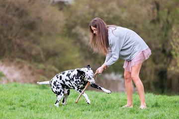young woman plays with her Dalmatian dog
