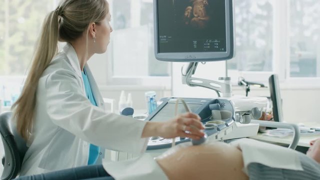 In the Hospital, Pregnant Woman Getting Sonogram / Ultrasound Screening / Scan, Obstetrician Checks Picture of the Healthy Baby on the Computer Screen. Doctor Talks with Happy Future Mother.