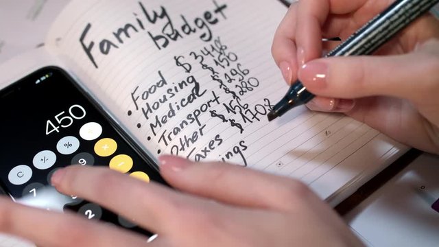 Woman calculate family budget on calculator and writing in notebook. Family budget calculation. Home accounting and domestic finances managing. Family finance concept