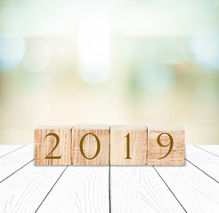 2019 new year greeting card, wooden cubes with 2019 on wood table over blur bokeh background with copy space for text, new year template