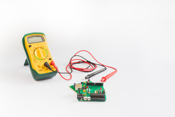 Electrical multimeter and PCB board on white background.