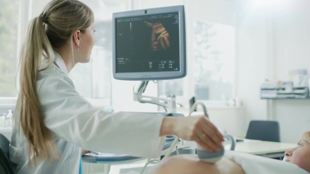In the Hospital, Obstetrician Uses Transducer for Ultrasound/ Sonogram Screening / Scanning Belly of the Pregnant Woman. Computer Screen Shows 3D Image of the Healthy Forming Baby. 