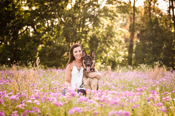 Young woman with German Shepherd dog in the gorgeous summer field