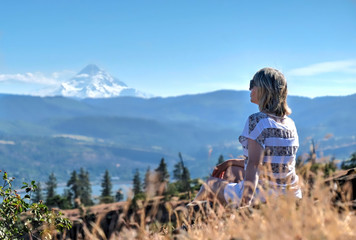 Woman in grass with view of Mount Hood. Columbia River Gorge. Catherine creek. Columbia River Gorge. The Dalles. Oregon. United States of Amrica.