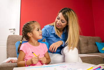 Mother interacting with her cute little girl, playing, drawing and having fun 