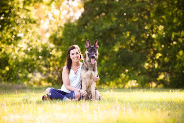 Young woman with German Shepherd dog in the gorgeous summer field