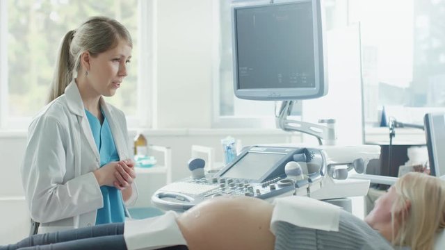 In the Hospital, Pregnant Woman Getting Sonogram / Ultrasound Screening / Scan, Obstetrician Checks Picture of the Healthy Baby on the Computer Screen. Doctor Explains Details of the Picture. 