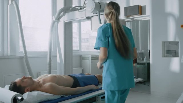 In the Hospital, Man Lying on a Bed, Female Technician adjusts X-Ray Machine. Shot on RED EPIC-W 8K Helium Cinema Camera.