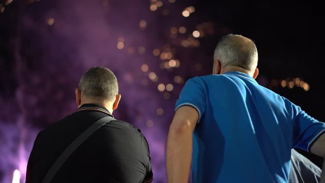 Men watching fireworks.  People standing on the background of colorful sky and looking fireworks