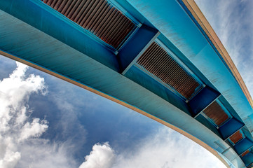 Underneath a freeway overpass on a sunny day with clouds in the sky
