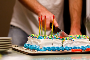Man cutting bright and colorful birthday cake.