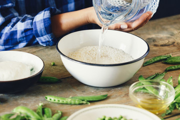 Healthy food concept Woman cooking vegetarian risotto green peas mint goat cheese Rustic style Raw ingredients cooking risotto wooden table