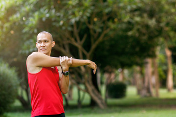 Asian man stretching in the park before running at the morning. Healthy lifestyle concept with copy space.