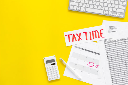 Tax Time Lettering On Office Work Desk With Calendar And Bills On Yellow Background Top View Copy Space