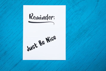 Reminder to Just Be Nice still life motivational concept on blue