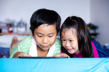 Asian children watching video and playing game on digital tablet.