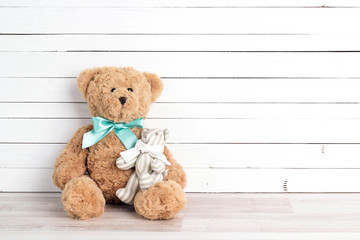 Two toy bears of parent and child on white wooden background. Parenthood concept. Copy space.