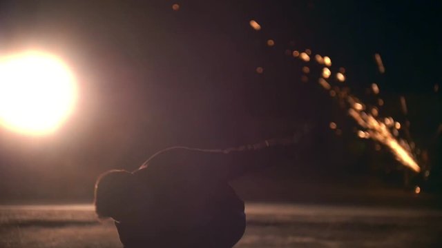 Tricking sport - man performs acrobatic tricks in front of bright sparkles - slow-motion