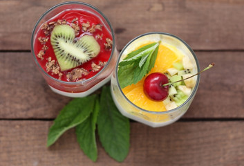 two glasses of Panna cotta dessert with cherries, orange and mint